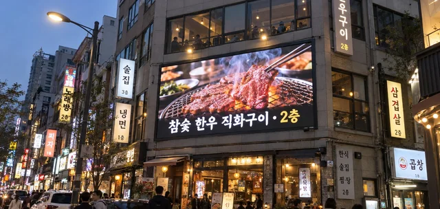 상가 건물 외벽 옥외 LED 전광판에 음식점 광고가 표시된 초저녁 거리 모습